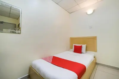 a small bedroom with a bed with a red pillow at Hotel River Inn in Butterworth