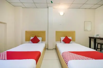 two beds with red pillows in a room at Hotel River Inn in Butterworth