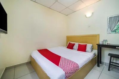 a bedroom with a bed with red pillows and a desk at Hotel River Inn in Butterworth