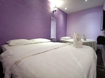 a bedroom with two beds with a purple wall at Juru Hotel in Bukit Mertajam