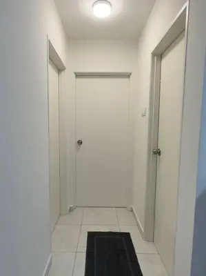 a hallway with two white doors and a black rug at TheSun #BayanLepas#QueensbayMall#PISA#USM in Bayan Lepas