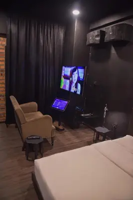a bedroom with a bed and a tv and a chair at The Label Suites Ipoh in Ipoh