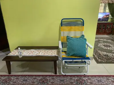 a chair with a pillow and a table in a room at D’baroh Homestay in Kampong Tanjong Karang