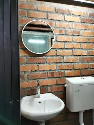 a bathroom with a sink and a mirror on a brick wall at D'RUMAH BONDA RIVER VIEW Kuala Kangsar in Kampong Senawar